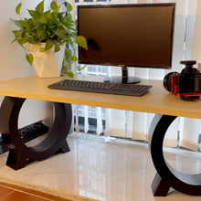 Load image into Gallery viewer, Modern desk setup with matte black circle metal legs, wooden tabletop, monitor, keyboard, potted plant, and mug on glossy floor.