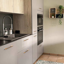 Load image into Gallery viewer, Modern kitchen with champagne bronze drawer handles on light gray cabinets, featuring a sleek sink and wall-mounted plants.