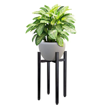 Load image into Gallery viewer, Adjustable metal plant stand in matte black holding a potted plant, featuring a reversible design for indoor and outdoor use.
