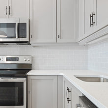 Load image into Gallery viewer, Modern kitchen with oil rubbed bronze drawer pulls on white cabinetry and stainless steel appliances.