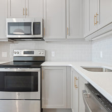 Load image into Gallery viewer, Modern kitchen featuring champagne bronze drawer handles on cabinets with stainless steel appliances